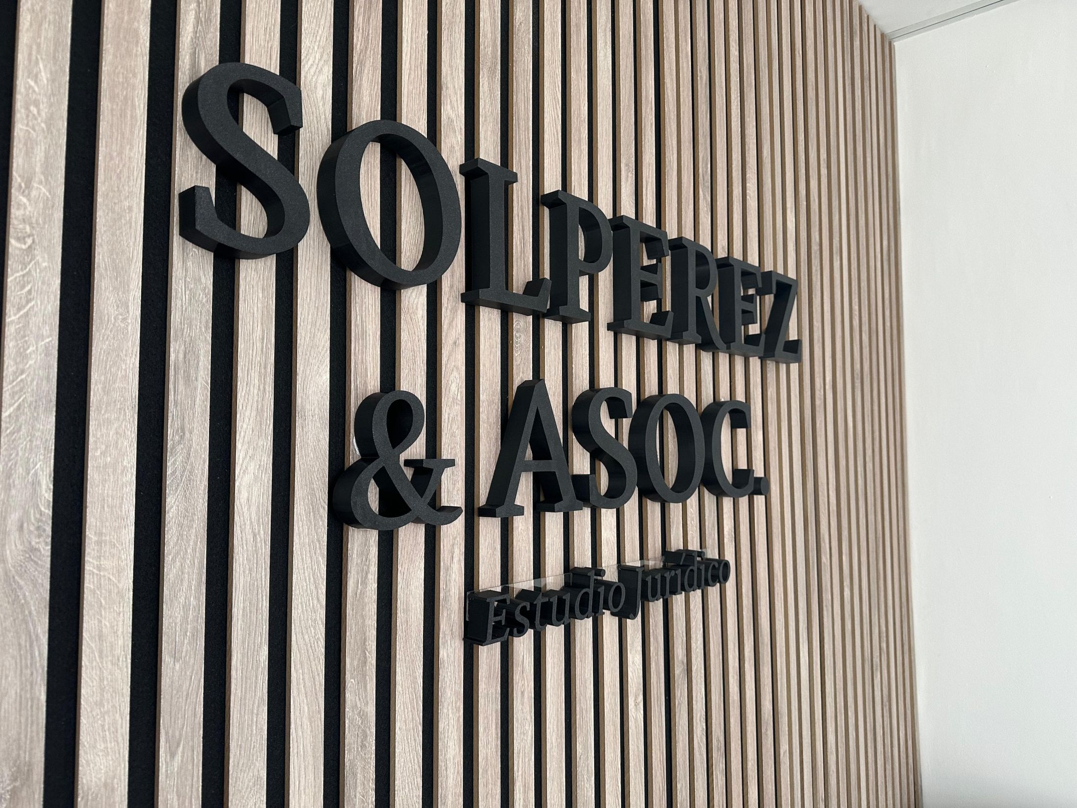 Primer plano de las letras en relieve del estudio sobre una pared de madera.